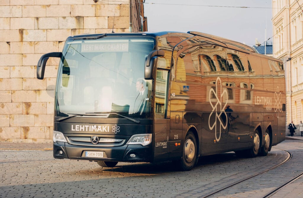 A black bus on a cobblestone street.