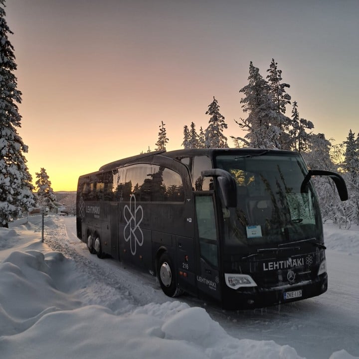 Musta bussi pysäköitynä lumiselle tielle.